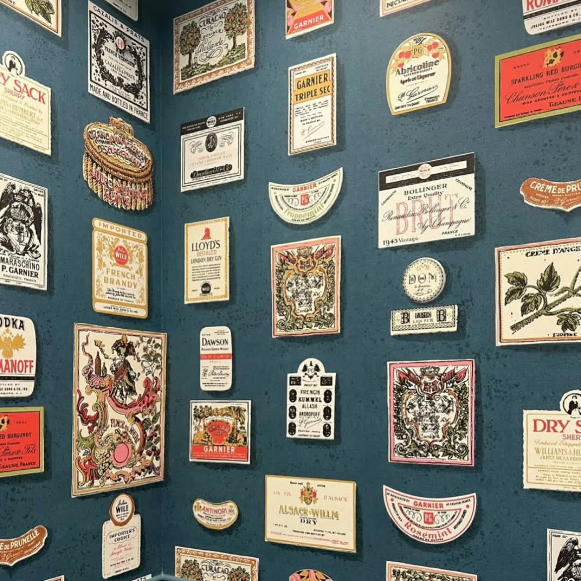 the perfect balance of charming and sophisticated, salud is a playful update on a 1950’s schumacher archival design of the same name. this storied design, featured in the 1995 cooper hewitt exhibition - kitsch to corbusier: wallpaper from the 1950's, highlights multi-colored hand-illustrated liquor labels in a graphic layout. this lively wide-width design will bring maximalist impact to any space. by Backdrop. – Living Room, Office, Featured Review, Wallcoverings